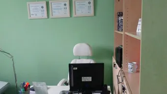 Despacho de Quirodiet con mesa, monitor, silla y diplomas en la pared